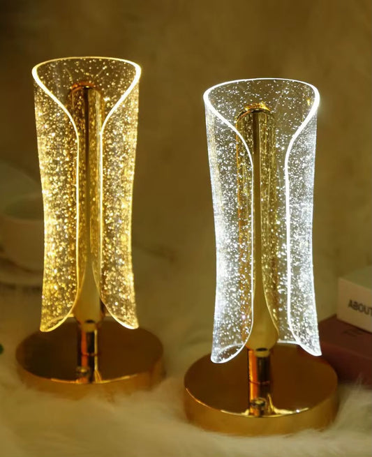 LED table lamp featuring a gold base and a sparkle-filled cylinder shade.